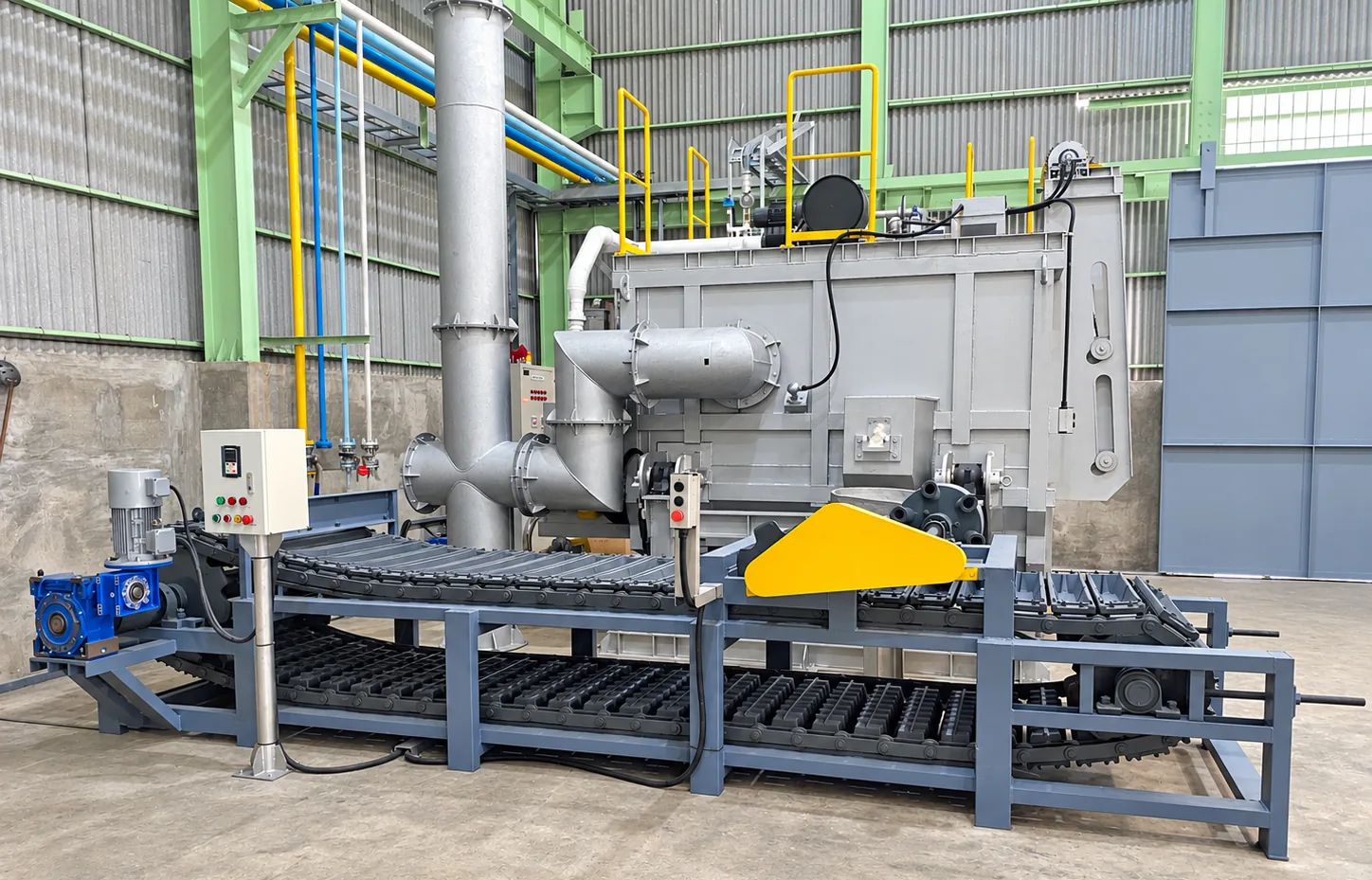 Ingot casting conveyor with moulds, drive and control panel in front of a furnace with exhaust stack inside a plant