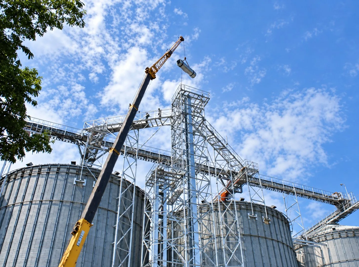 Crane lifting equipment onto a steel structure at an industrial plant