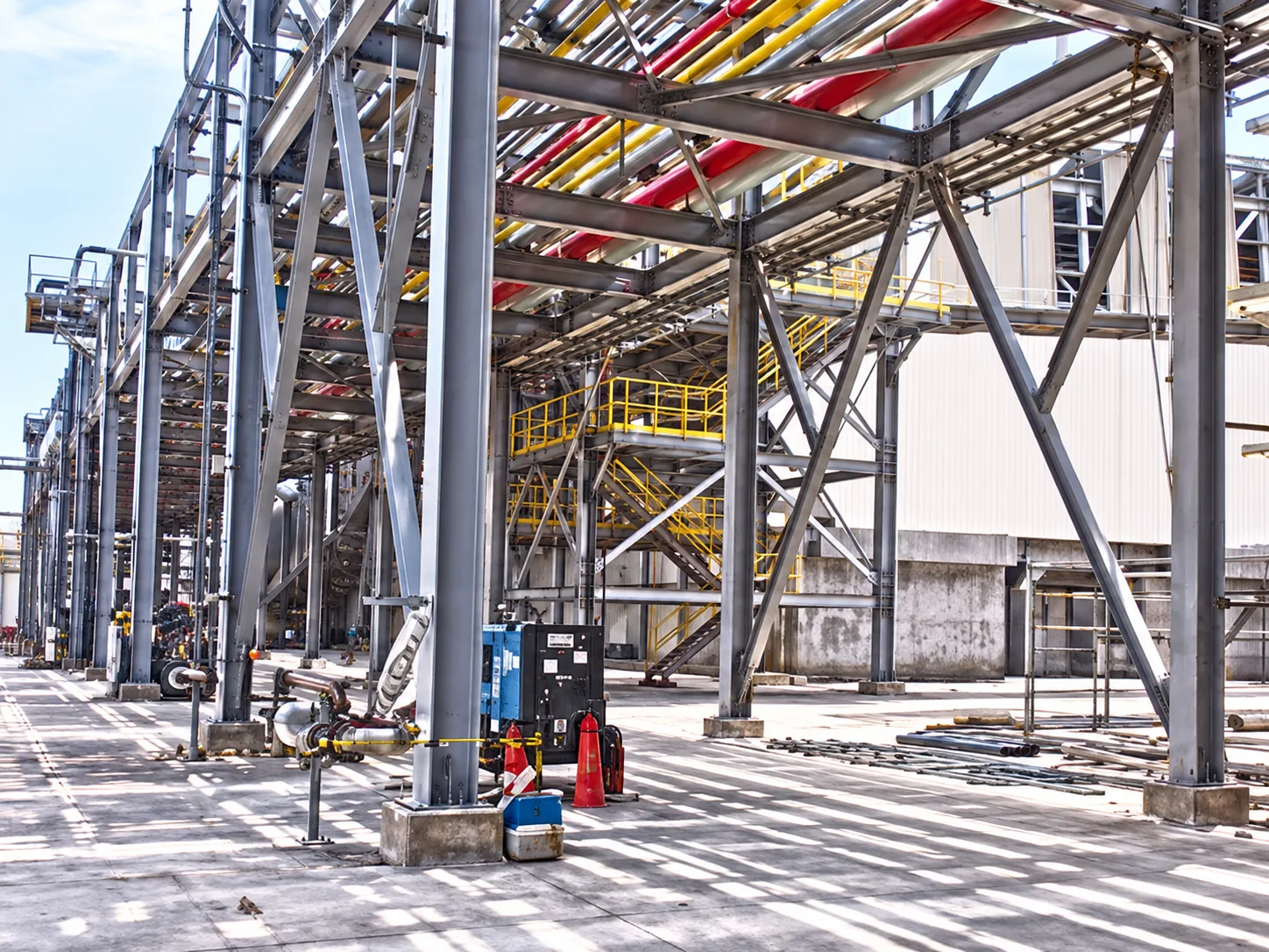 Steel pipe rack structure carrying multiple colored pipelines, with stairs and platforms