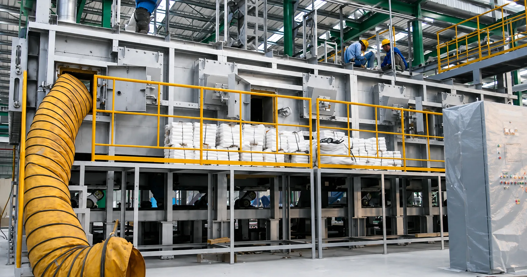 MWT tempering furnace under fabrication in the workshop, with steel casing, access platform with yellow railings, insulation material on site, ventilation duct and control panel
