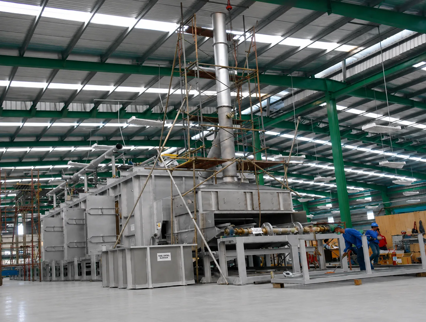 MWT industrial heating furnace under fabrication in the MWT workshop, with casing sections, exhaust stack, burner control panel and roller drive frame